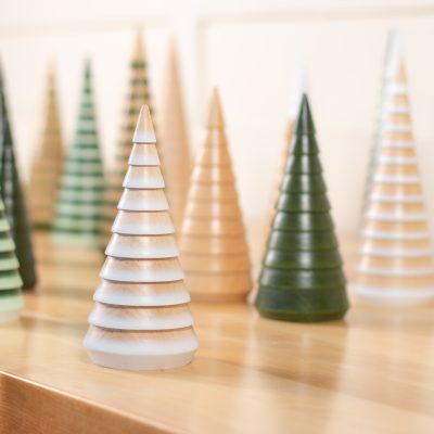 A collection of little tabletop wooden fir trees in various colors and sizes.
