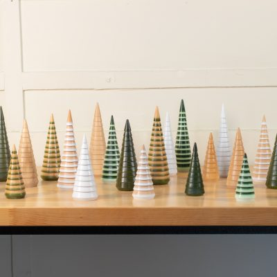 A wooden Christmas tree set displayed on a countertop in an assortment of colors and sizes.
