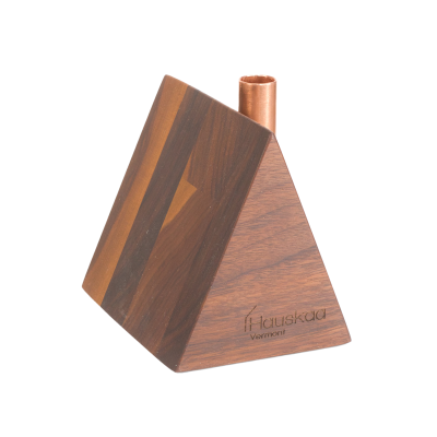 A tiny wooden a-frame house candlestick holder with a copper chimney.