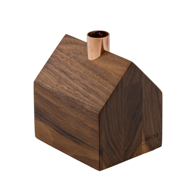 A tiny wooden house candlestick holder with a copper chimney.