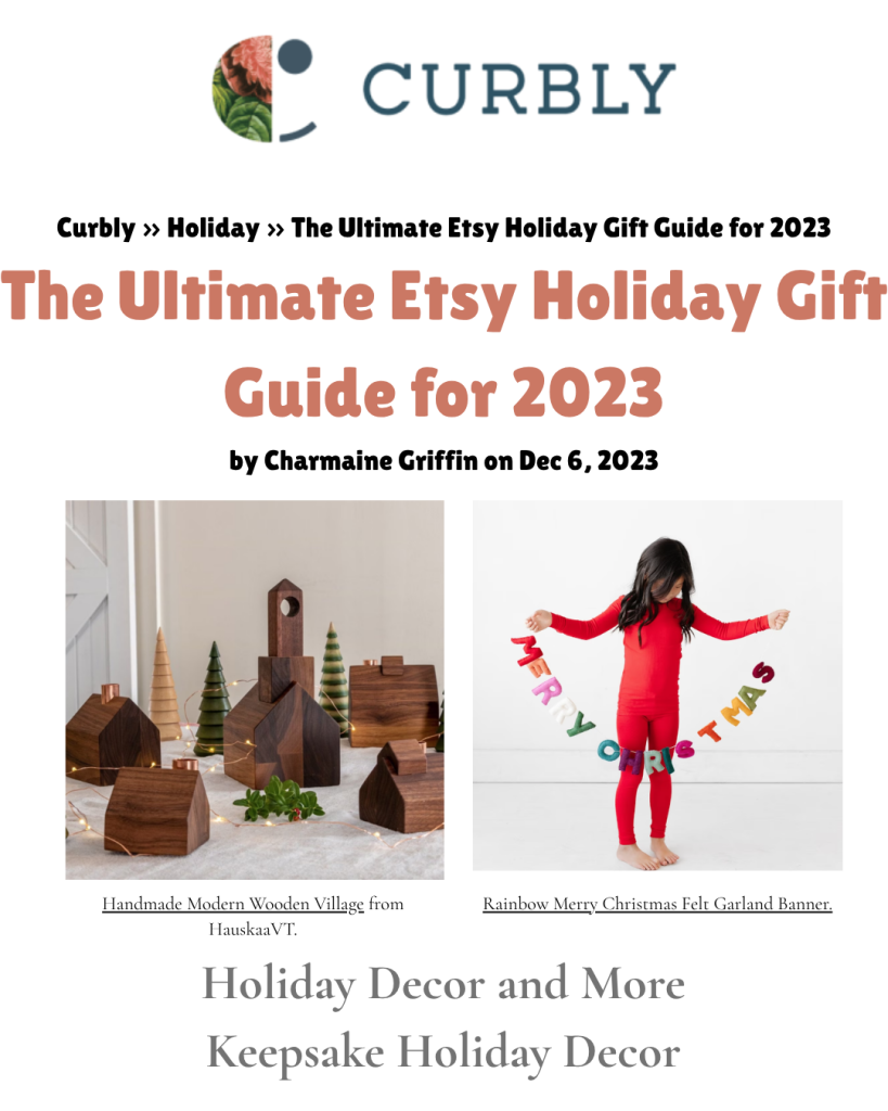 Curbly feature highlighting Hauskaa. The image displays the Curbly logo and the breadcrumb text: ‘Curbly ›› Holiday ›› The Ultimate Etsy Holiday Gift Guide for 2023.’ The headline reads: ‘The Ultimate Etsy Holiday Gift Guide for 2023,’ followed by ‘by Charmaine Griffin on Dec 6, 2023.’ Below are two product photos: on the left, a wooden holiday village with the caption ‘Handmade Modern Wooden Village from HauskaaVT,’ and on the right a child holding a colorful felt banner with the caption ‘Rainbow Merry Christmas Felt Garland Banner.’ Additional text at the bottom reads: ‘Holiday Decor and More Keepsake Holiday Decor.’